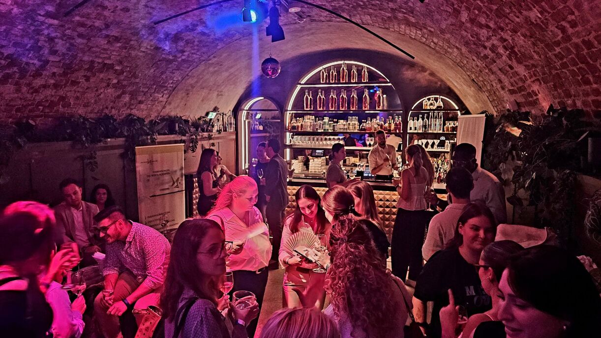 Personen, die in einem dunklen Gewölbe zusammenstehen und freudige Gesichter zeigen.