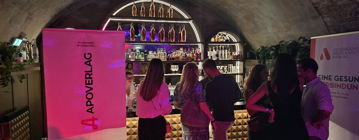 Personen in einem dunklen Raum, stehend an einer Getränkebar.